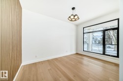 Expansive room featuring wood-finish flooring, a full-height slatted accent wall, and a large black-framed window - 