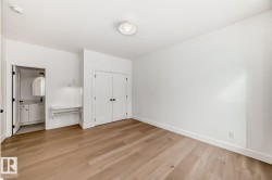 Spacious room featuring light wood-finish flooring, white walls, and a ceiling-mounted light fixture - 