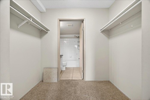Walk-in closet featuring plush carpet flooring, light-toned walls, and twin built-in shelving units with hanging rods - 112 6710 158 Avenue, Edmonton, AB 