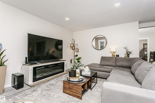 Living area featuring an electric fireplace with a white and wood-finish mantel, recessed ceiling lighting, and light-toned wall finishes - 5610 57 Avenue, Beaumont, AB 