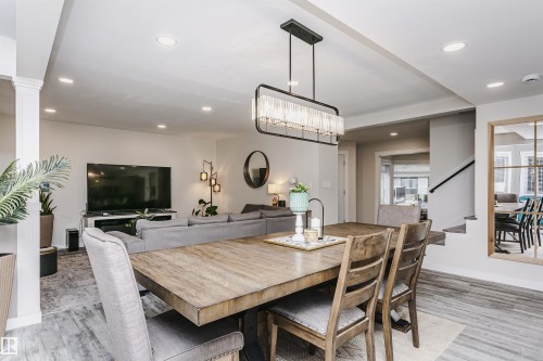 Spacious dining area featuring a rectangular wood-finish table and an overhead linear chandelier - 5610 57 Avenue, Beaumont, AB 