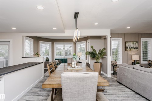 Open-concept floor plan featuring a dining area with a linear chandelier, recessed lighting, and wood-finish flooring - 5610 57 Avenue, Beaumont, AB 
