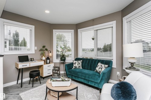Spacious living area featuring multiple windows with blinds, wood-finish flooring, recessed lighting, and neutral wall tones - 5610 57 Avenue, Beaumont, AB 
