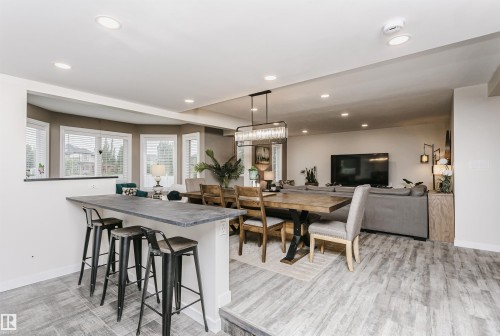 Open-concept living space featuring wood-finish flooring, recessed lighting, and a prominent breakfast bar with a stone-finish countertop - 5610 57 Avenue, Beaumont, AB 
