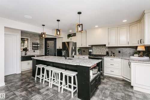 Spacious kitchen featuring a large central island with seating, granite countertops, and wood-finish flooring - 5610 57 Avenue, Beaumont, AB 