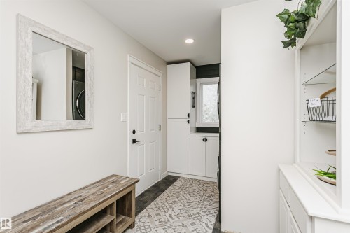 Entryway with light-toned walls, a decorative mirror, and a built-in storage bench - 5610 57 Avenue, Beaumont, AB 