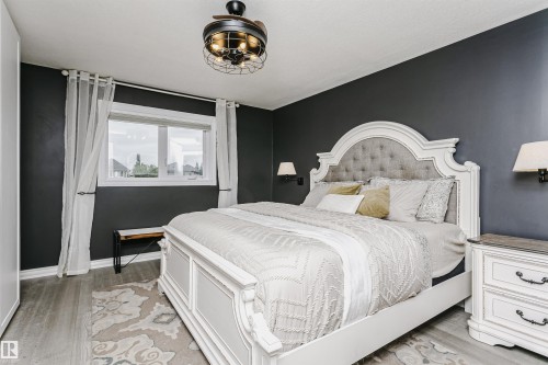 Spacious room featuring wood-finish flooring, a contemporary ceiling fan, and a large window with white trim - 5610 57 Avenue, Beaumont, AB 