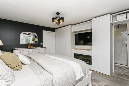 Integrated fireplace with wood-finish mantel, built-in cabinetry, and a modern industrial ceiling fan - 5610 57 Avenue, Beaumont, AB 