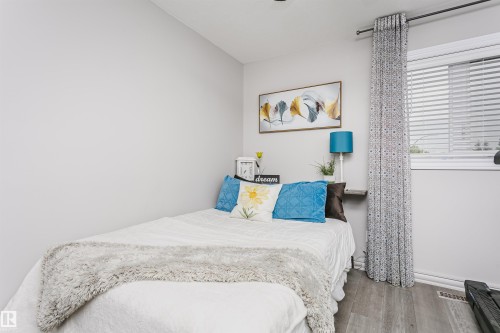 Light-filled room featuring wood-finish flooring and a window with blinds - 5610 57 Avenue, Beaumont, AB 