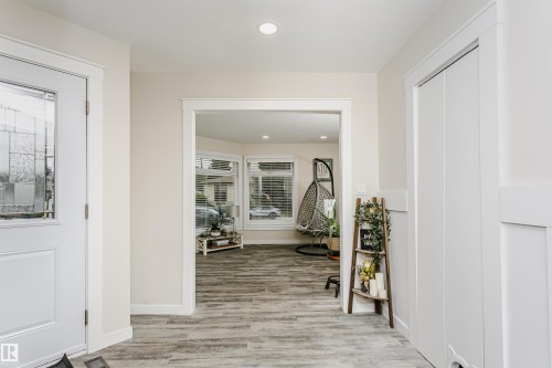 Entryway featuring a white door with decorative glass, recessed lighting, wood-finish flooring, and a white paneled wall - 5610 57 Avenue, Beaumont, AB 