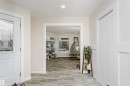 Entryway featuring a white door with decorative glass, recessed lighting, wood-finish flooring, and a white paneled wall - 5610 57 Avenue, Beaumont, AB 