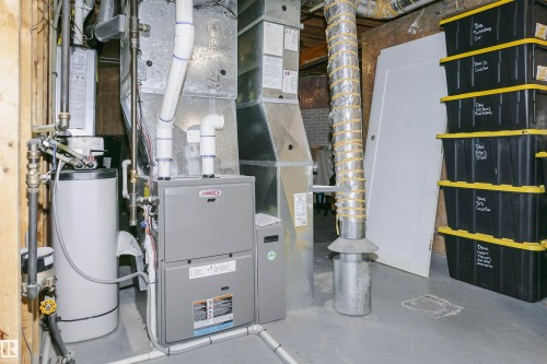 Utility room featuring a Lennox furnace and a water heater, with exposed ductwork and plumbing - 5610 57 Avenue, Beaumont, AB 