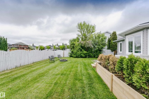Expansive backyard featuring a manicured lawn, a white picket fence, and mature trees - 5610 57 Avenue, Beaumont, AB 