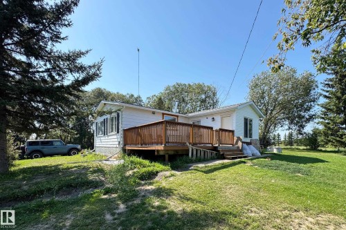White siding residence featuring a spacious wooden deck with railings, an accessibility ramp, and stairs - 3054 28 Avenue, Edmonton, AB 