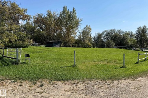 Expansive green space featuring a split-rail fence, mature trees, and a gravel driveway - 3054 28 Avenue, Edmonton, AB 