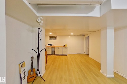 Spacious lower level featuring light wood-finish flooring, recessed lighting, white walls, and a built-in workstation with light wood countertops and white cabinetry - 3054 28 Avenue, Edmonton, AB 