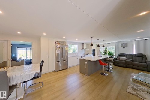 Open-concept living space featuring wood-finish flooring, recessed lighting, and a kitchen island with pendant lights - 3054 28 Avenue, Edmonton, AB 