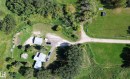 Expansive property featuring a gravel driveway, multiple structures with light-colored roofing, a manicured lawn, and mature trees - 3054 28 Avenue, Edmonton, AB 