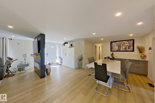 Open-concept living space featuring wood-finish flooring, recessed lighting, and a modern partial wall with a built-in fireplace - 3054 28 Avenue, Edmonton, AB 
