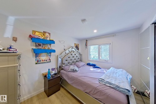 Bedroom featuring recessed lighting, a window with exterior views, wood-finish flooring, and built-in mirrored wardrobe doors - 3054 28 Avenue, Edmonton, AB 
