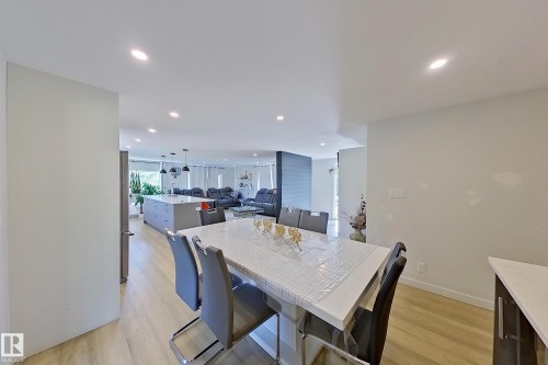 Dining area featuring a white rectangular table with seating for six, wood-finish flooring, and recessed ceiling lighting - 3054 28 Avenue, Edmonton, AB 