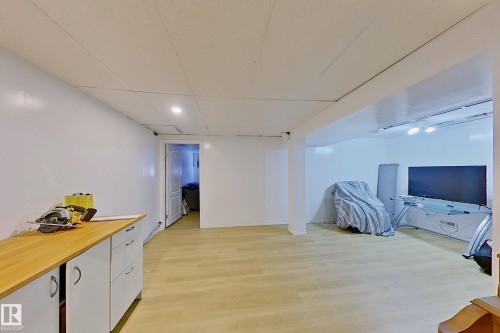 Spacious room featuring wood-finish flooring, white walls, and a drop ceiling with recessed lighting - 3054 28 Avenue, Edmonton, AB 