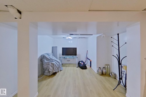 Open concept interior space featuring light wood-finish flooring, white walls, and a dropped acoustic ceiling - 3054 28 Avenue, Edmonton, AB 