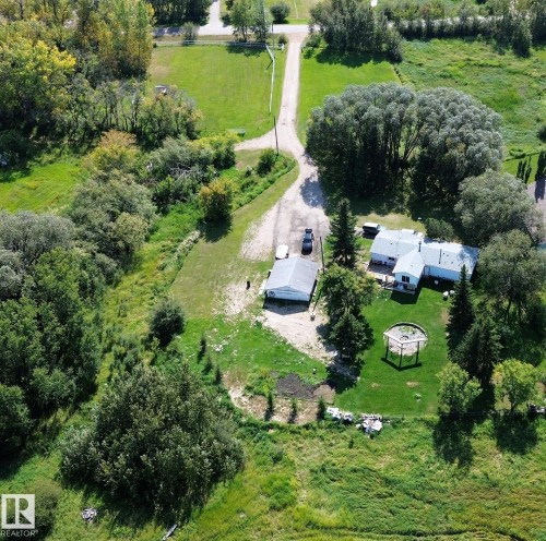 Expansive property featuring a gravel driveway, detached garage, and a single-story residence - 3054 28 Avenue, Edmonton, AB 