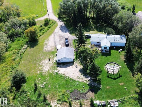 Expansive property featuring a detached outbuilding, a circular fire pit area with a pergola, and mature trees bordering the perimeter - 3054 28 Avenue, Edmonton, AB 