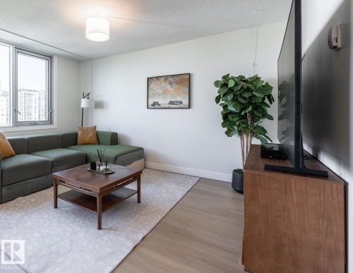 Living area featuring light wood-finish flooring, white walls, and large windows - 807 10011 116 Street, Edmonton, AB 