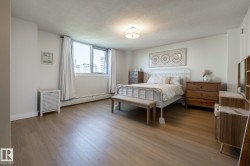 Spacious room featuring wood-finish flooring, a large window with white window treatments, and a flush-mount ceiling light fixture - 