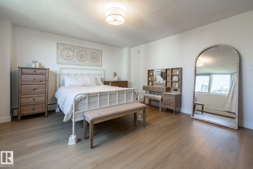 Spacious room featuring wood-finish flooring, white painted walls, and a contemporary flush-mount ceiling light fixture - 807 10011 116 Street, Edmonton, AB 