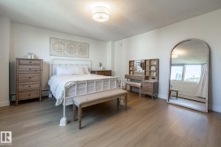 Spacious room featuring wood-finish flooring, white painted walls, and a contemporary flush-mount ceiling light fixture - 