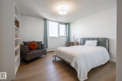 Bright living space featuring wood-finish flooring, a contemporary ceiling light fixture, and a large window with white trim - 