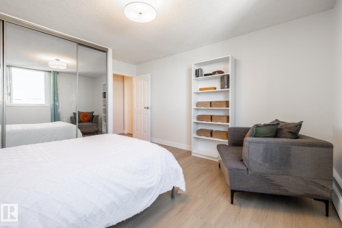 Bedroom featuring mirrored closet doors, wood-finish flooring, a contemporary ceiling light fixture, and a white interior door - 807 10011 116 Street, Edmonton, AB 
