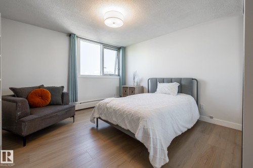 Light-filled room featuring wood-finish flooring, a contemporary flush mount ceiling light, white baseboards, and a window with a white frame - 807 10011 116 Street, Edmonton, AB 