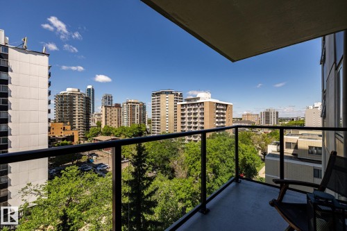 Balcony with glass railing overlooking mature trees and surrounding neighbourhood buildings - 807 10011 116 Street, Edmonton, AB 