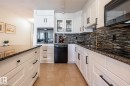 Gourmet kitchen featuring white shaker cabinetry, black hardware, dark countertops, a mosaic tile backsplash, and a built-in oven with a microwave - 807 10011 116 Street, Edmonton, AB 