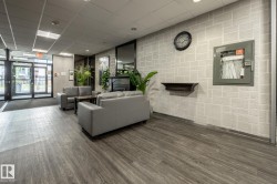 Lobby area featuring wood-finish flooring, a decorative fireplace, and an exposed brick-pattern wall - 