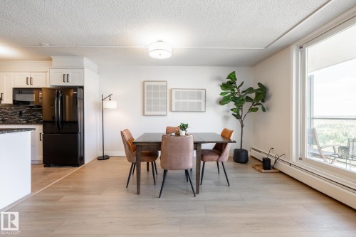 Open-concept dining area featuring wood-finish flooring, a contemporary ceiling light fixture, and a large window - 807 10011 116 Street, Edmonton, AB 