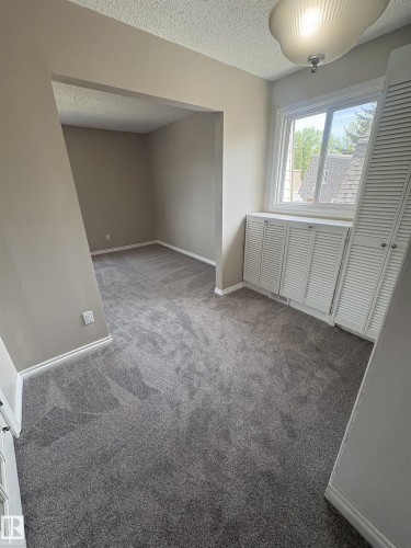 Room featuring new gray carpeting throughout, neutral wall paint, and a white window frame - 11 Greenfield Estates, St. Albert, AB 
