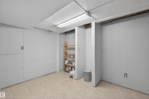 Unfinished interior space featuring drywall paneling, a suspended acoustic tile ceiling, and ceramic tile flooring - 11 Greenfield Estates, St. Albert, AB 