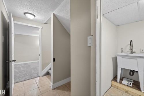Utility area with a white laundry sink and brushed nickel pull-down faucet - 11 Greenfield Estates, St. Albert, AB 