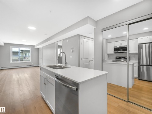 Kitchen island with a double basin sink, gooseneck faucet, and integrated dishwasher - 318 1506 Tamarack Boulevard, Edmonton, AB 