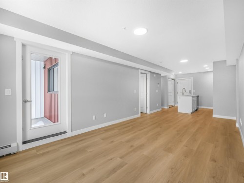 Open concept living area featuring light wood-finish flooring, neutral gray wall tones, and white trim - 318 1506 Tamarack Boulevard, Edmonton, AB 