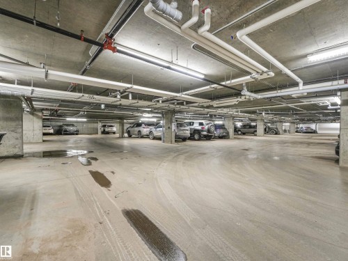 Underground parking garage featuring concrete flooring, exposed ceiling utilities, and columned structural supports - 318 1506 Tamarack Boulevard, Edmonton, AB 