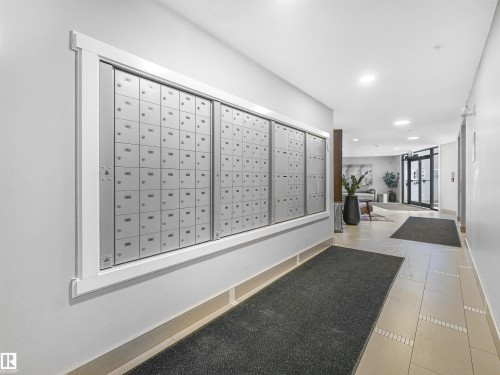 Building common area featuring a wall of individual mailboxes, neutral wall paint, and light-toned tile flooring - 318 1506 Tamarack Boulevard, Edmonton, AB 