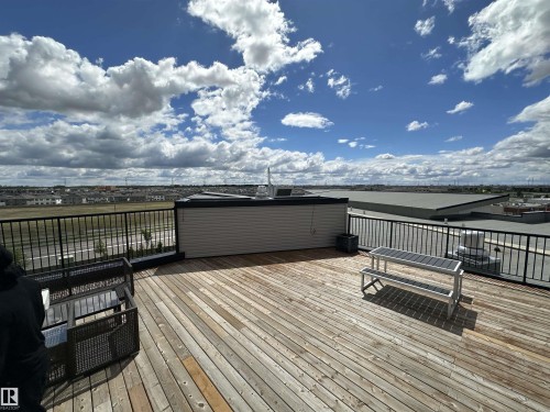 Expansive rooftop deck featuring wide plank wood flooring and a black metal railing - 318 1506 Tamarack Boulevard, Edmonton, AB 