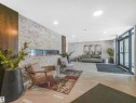 Contemporary lobby featuring a stone-clad wall with an elongated linear fireplace, recessed lighting, and large glass entry doors - 318 1506 Tamarack Boulevard, Edmonton, AB 