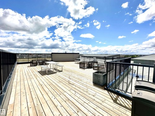 Expansive rooftop deck featuring wood-finish flooring, black metal railings, and concrete planters - 318 1506 Tamarack Boulevard, Edmonton, AB 